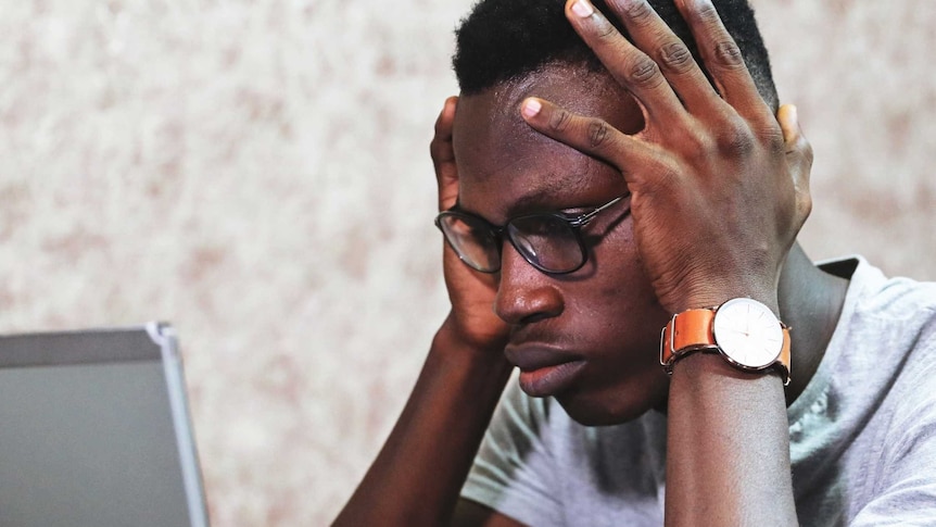 Man with head in hands looking confused at laptop for a story about understanding work payslips.