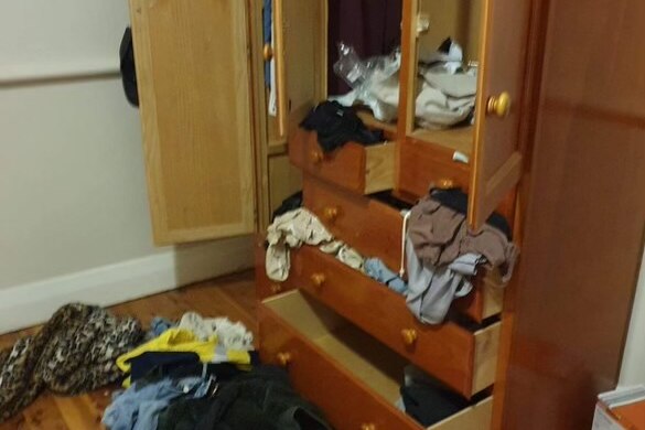 Picture of wardrobe, with doors open and clothes scattered through wardrobe and on floor 