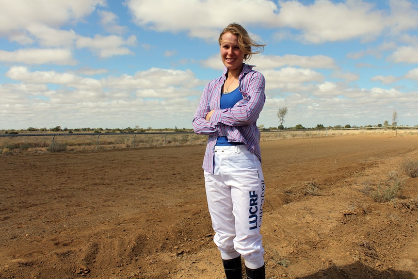 Jockey Amy Macintosh stands in front of of the race track