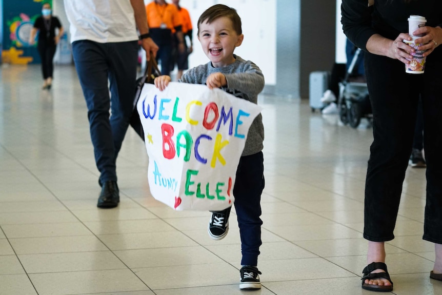 A grinning child runs to welcome his returning aunt as South Australia opens its borders to Victoria.