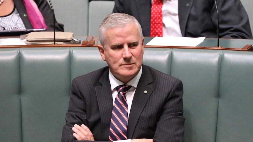 A man sitting alone with his arms crossed inside the House of Representatives