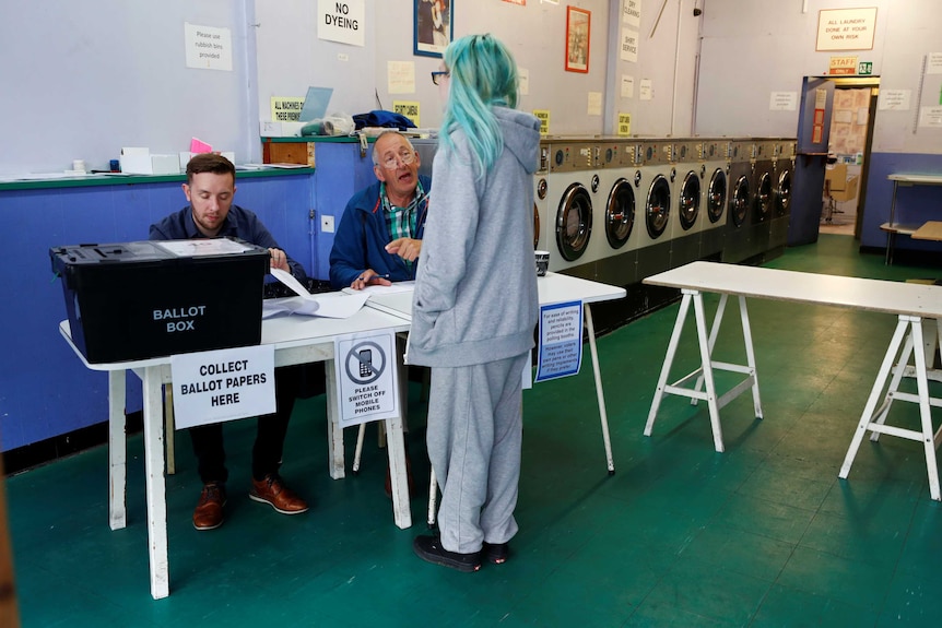 A woman with turquoise hair votes at a laundrette used as a temporary polling station in Oxford.
