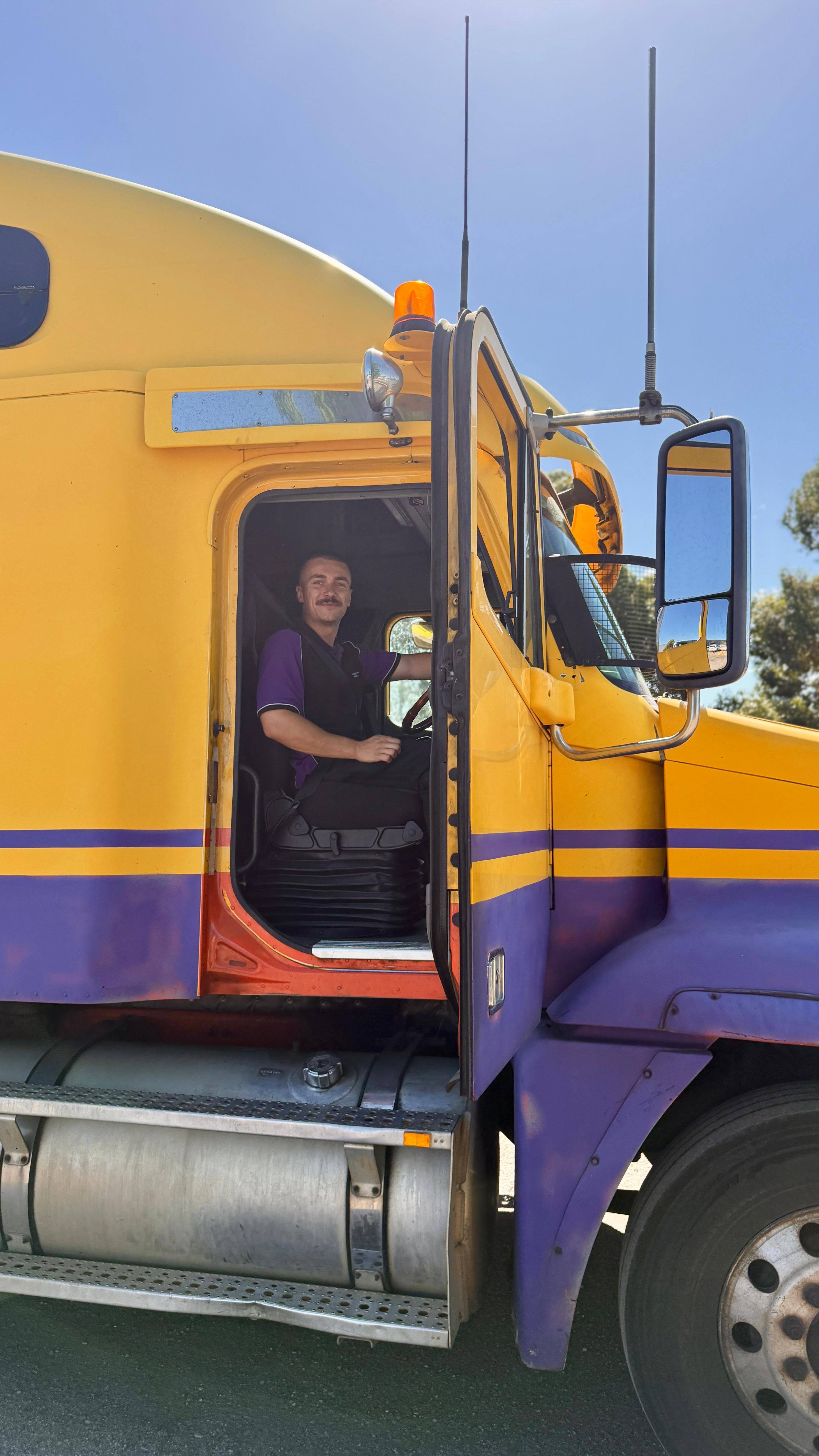 El joven sonríe desde la puerta del camión.