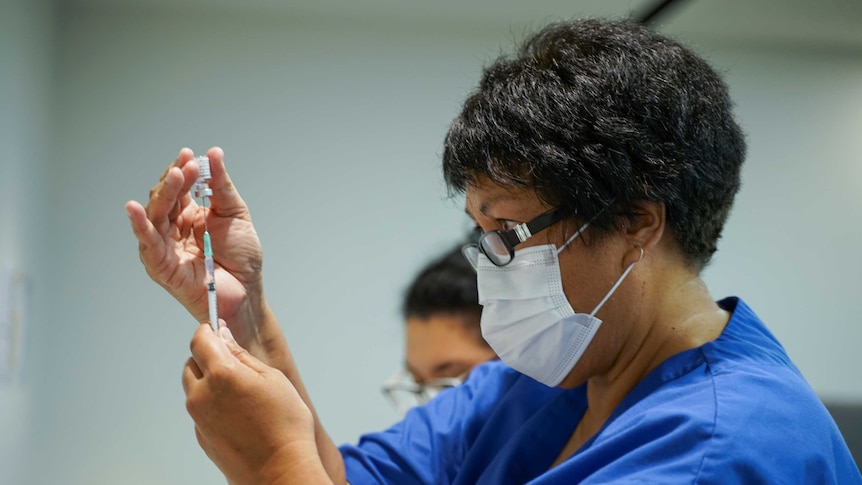 A healthcare worker fills a syringe with the Pfizer-BioNTech coronavirus vaccine