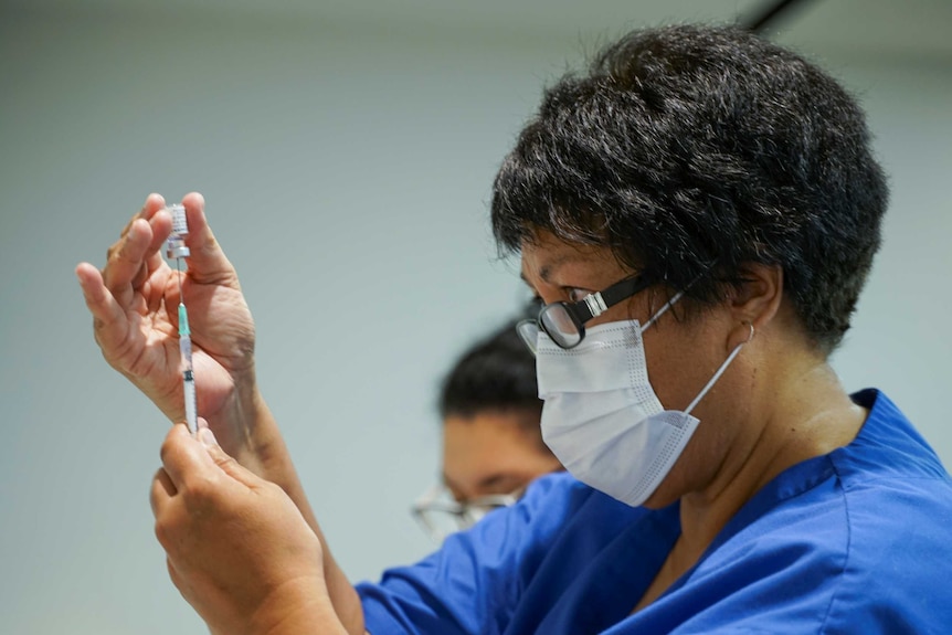 A healthcare worker fills a syringe with the Pfizer-BioNTech coronavirus vaccine