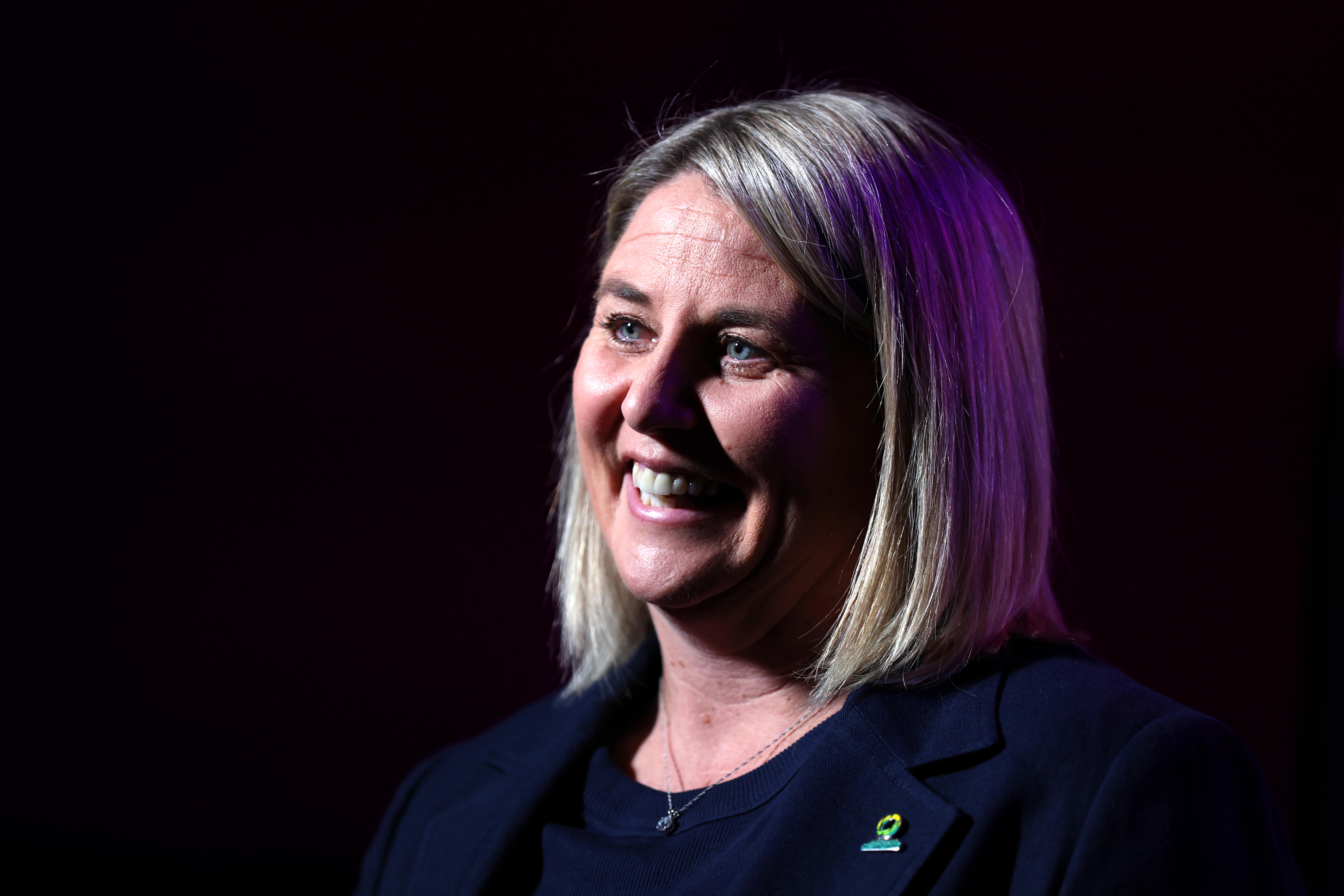 Stacey Marinkovich smiles for the camera in front of a black screen