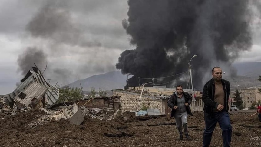 Two men flee as a building burns behind them.