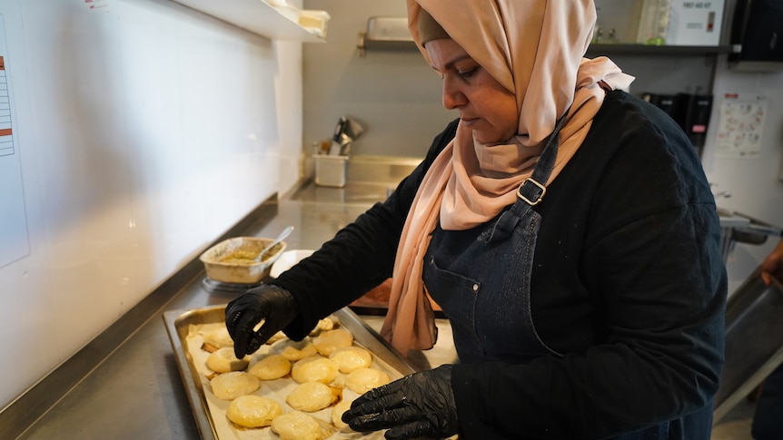 a woman in a hijab stands beside a plate of pastries