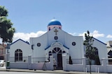 A white building with a dome with a blue painted roof