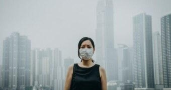 Young woman wearing protective face mask in city due to the polluted air