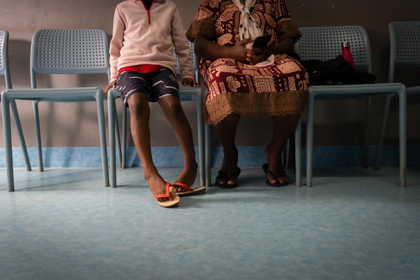 A photo of two patients sitting on chairs in the clinic.