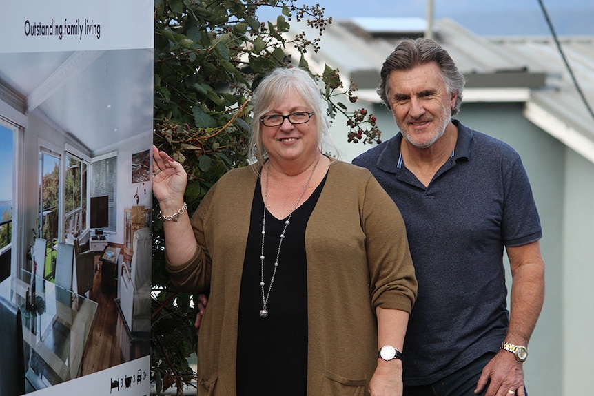 Geoff and Jo Winckle stand next to a for sale sign