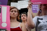Women hold signs to protest Georgia's anti-abortion laws.
