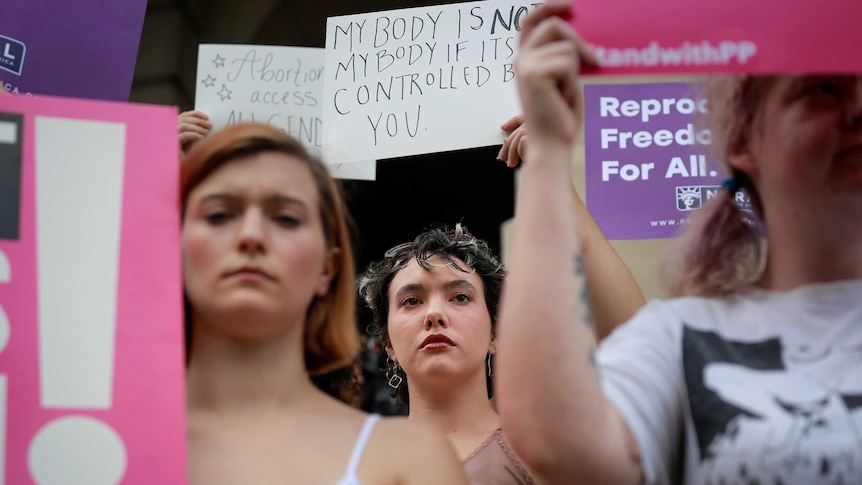 Women hold signs to protest Georgia's anti-abortion laws.