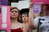 Women hold signs to protest Georgia's anti-abortion laws.
