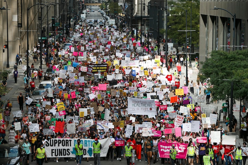 an above view of pro abortion protesters crowding the streets of chicago, holding up signs