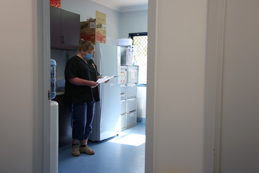 Health worker Kathryn Drummond reads and reads some paperwork in the kitchen of a clinic.