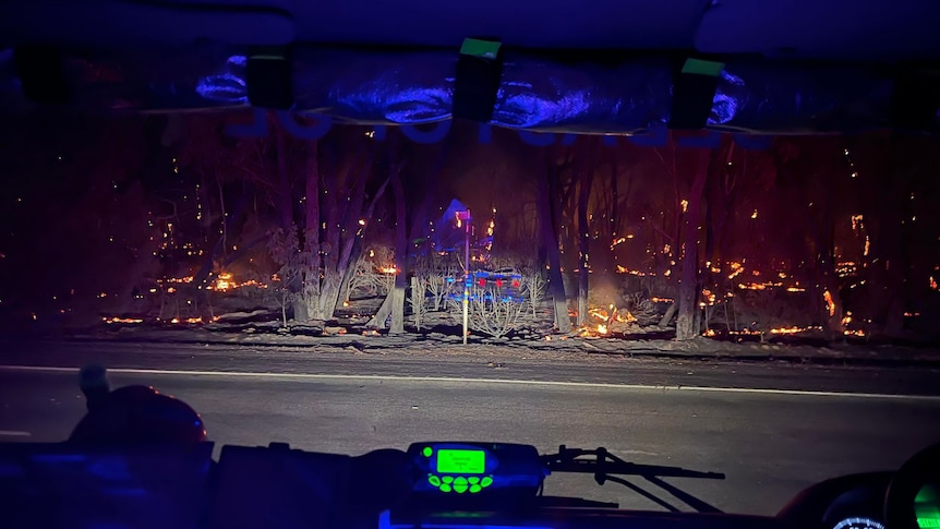 The dashboard of a fire truck with fire on the side of a road