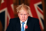 Britain's Prime Minister Boris Johnson stares forward in front of a British flag.