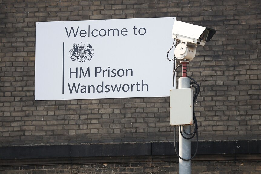 A security camera faces away from a sign that reads welcome to HM prison wandsworth