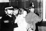 A black and white photo of the Yorkshire Ripper, with a blanket over his head, being taken into custody.