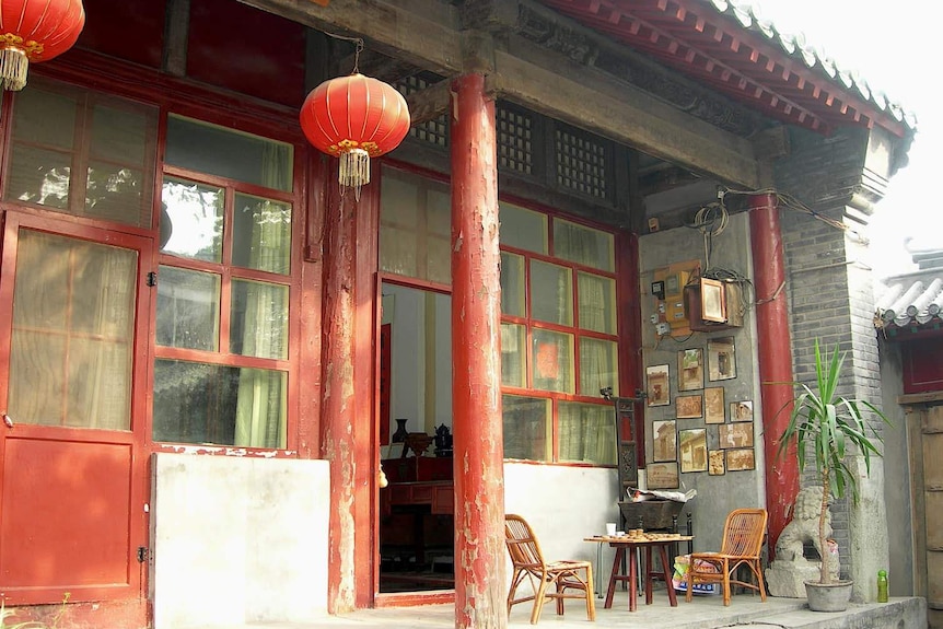 A photo of a brick structure with red columns and Chinese lanterns on its balcony
