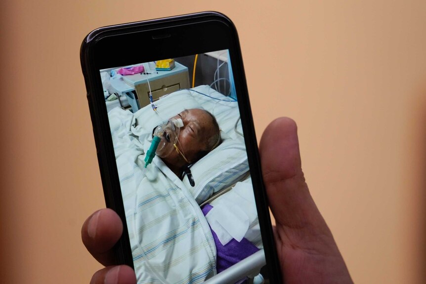 A mobile phone screen showing the photo of an old man in a hospital