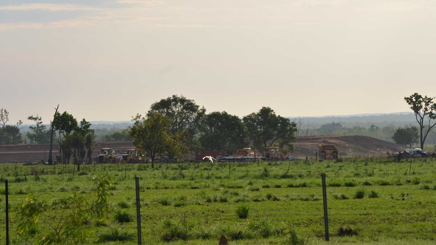 Earth moving equipment in front of the beginnings of a new dam