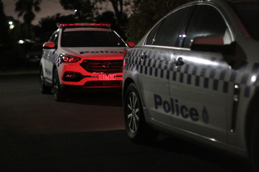 Two police vehicles parked on a suburban street at night.