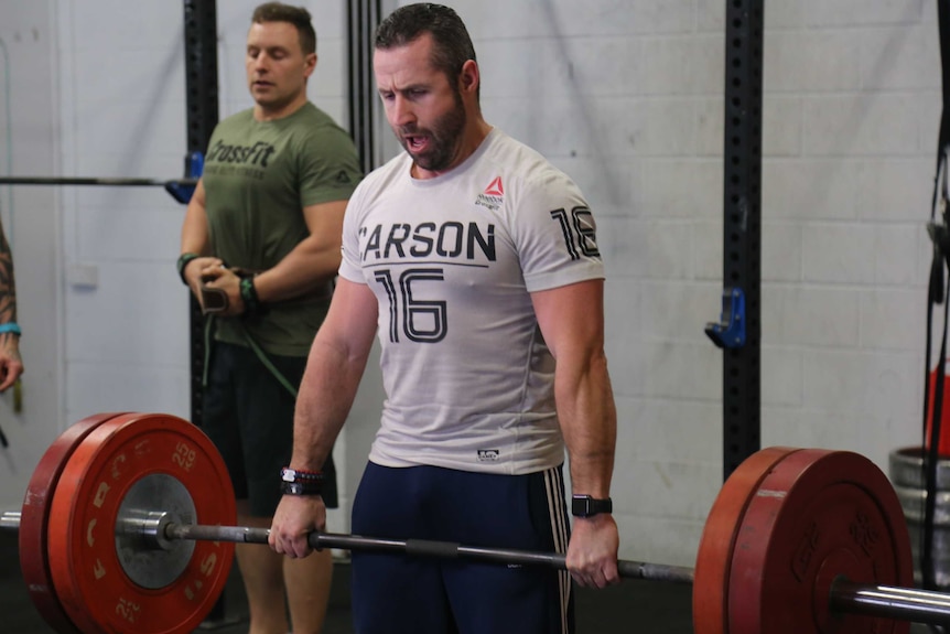 Brad Fewson lifts weights in the gym.