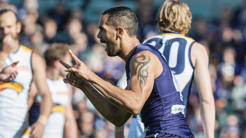 Shane Yarran of the Fremantle Dockers celebrates a goal with his arms raised.