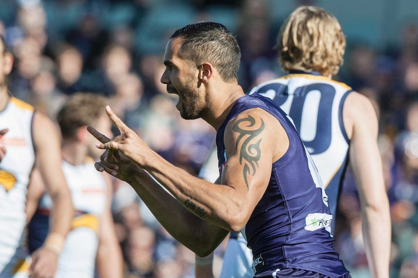 Shane Yarran of the Fremantle Dockers celebrates a goal with his arms raised.