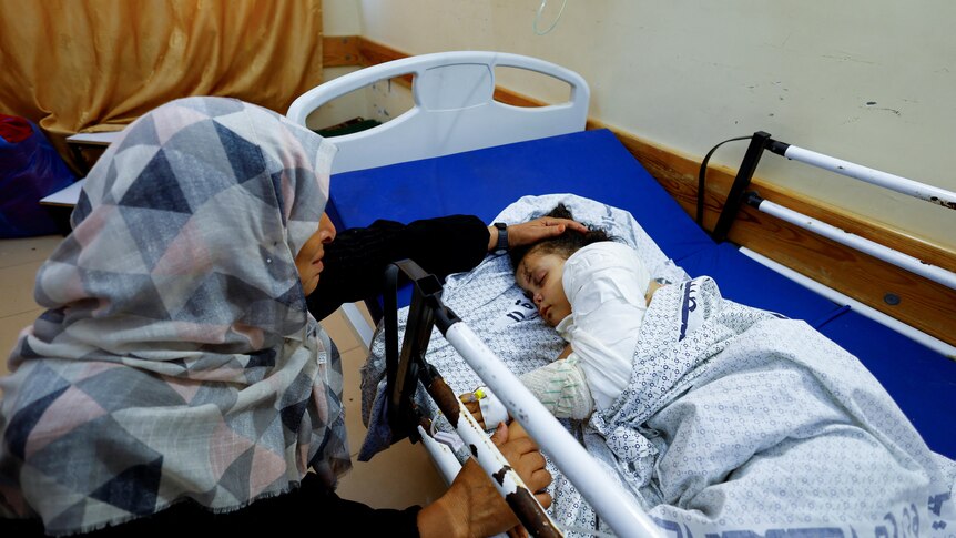a litlte girl lies in a hospital bed with her grandmother 