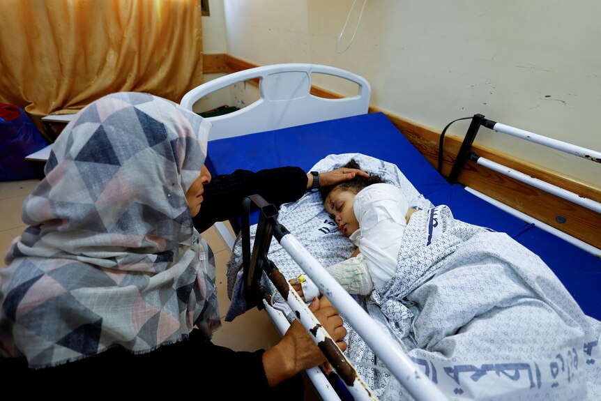 a litlte girl lies in a hospital bed with her grandmother 
