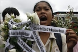 A student holds flowers for the victims of election-related violence in Philippines