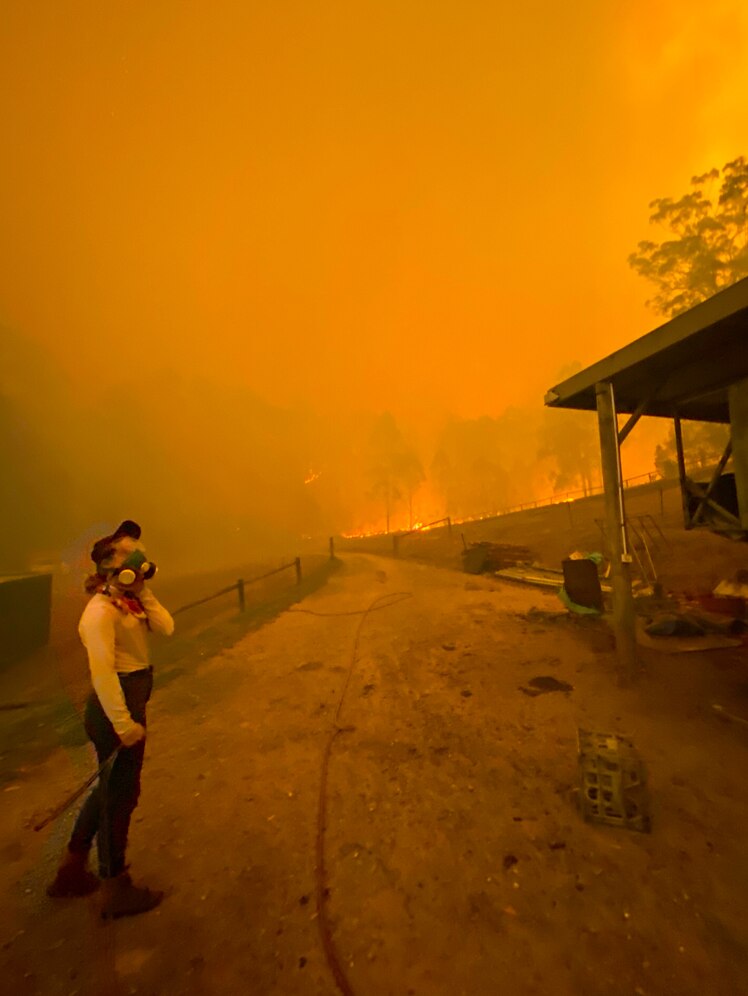 Girl in face mask, with orange sky and fire in background, pictured in story about children and bushfire trauma