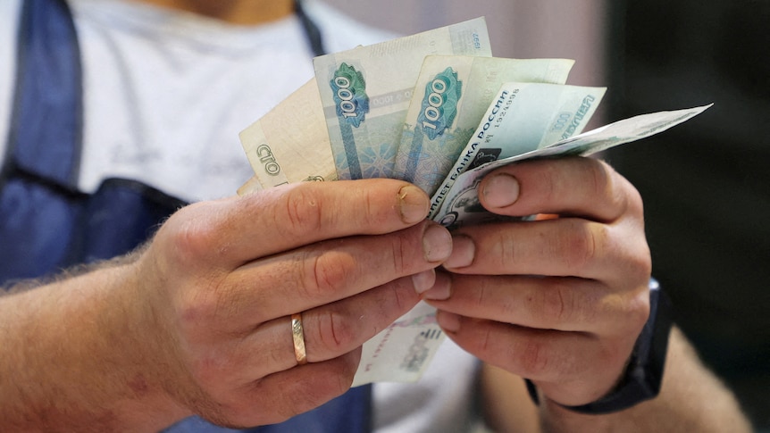 A vendor counts Russian rouble banknotes at a market in Saint Petersburg.