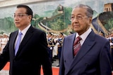 Li Keqiang and Mahathir Mohamad walk together past a guard of honour.