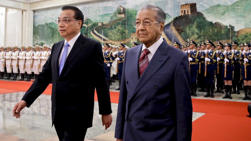 Li Keqiang and Mahathir Mohamad walk together past a guard of honour.