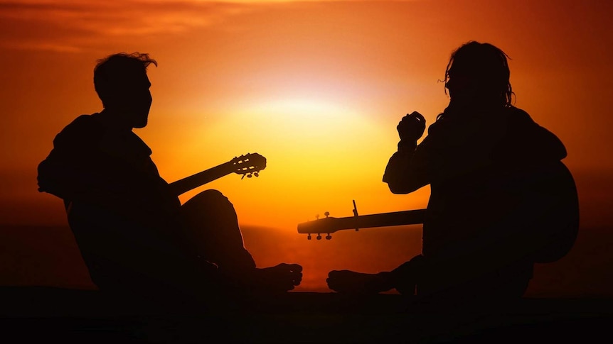 Two people with guitars outdoors for story about learning new things even if you're not good at them
