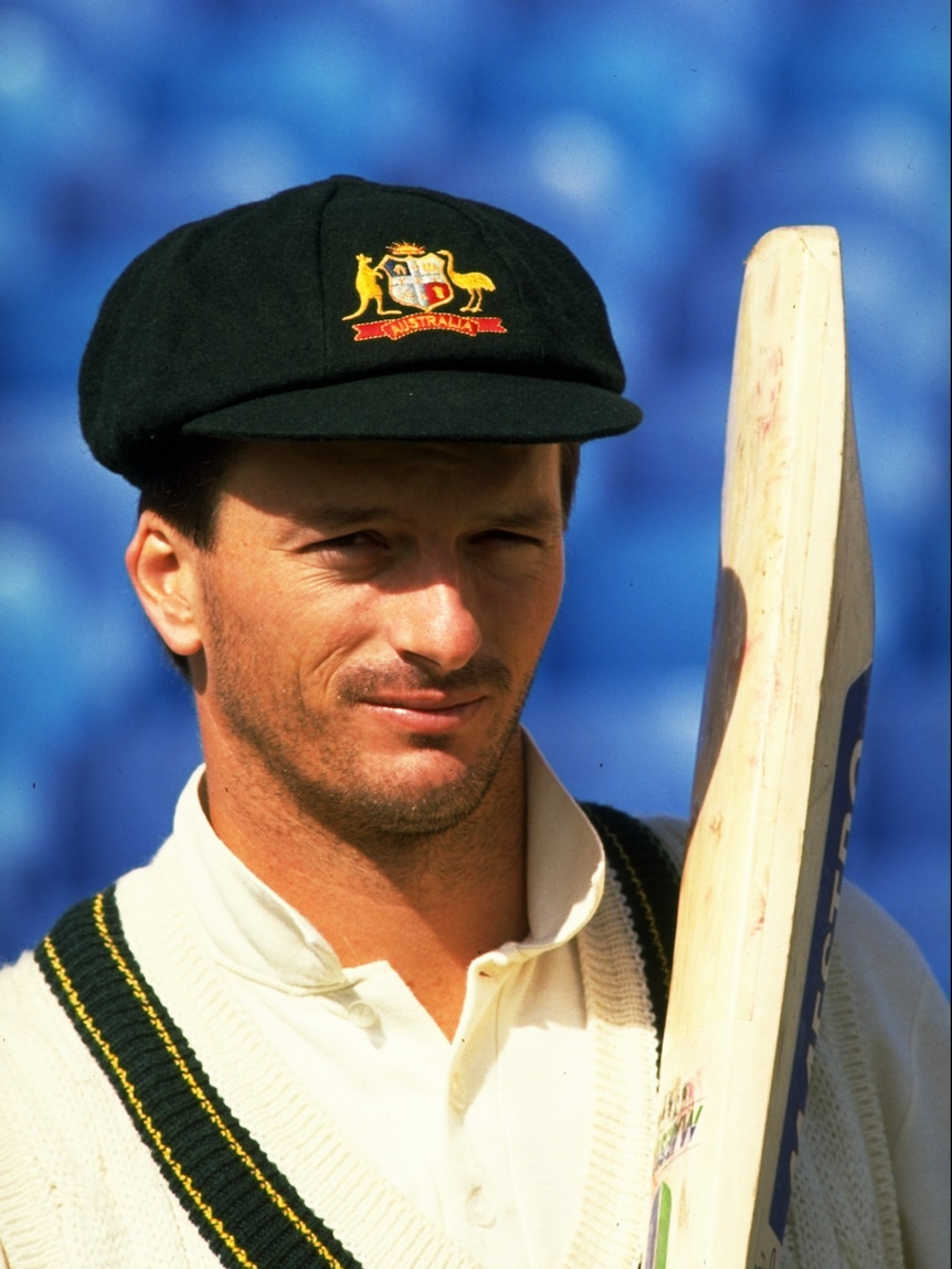 A portrait of a man with a bat and wearing a green cap
