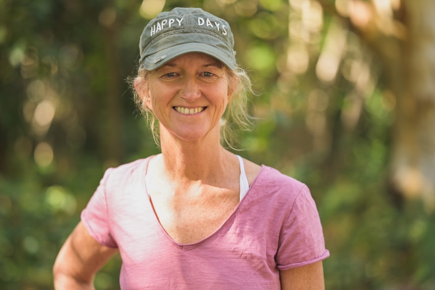 Nicole van Leeuwen, North Stradbroke Island resident of 31 years and teacher, smiling with trees behind her