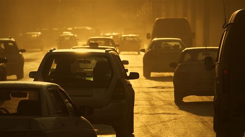 Smoggy looking highway with cars driving down it.