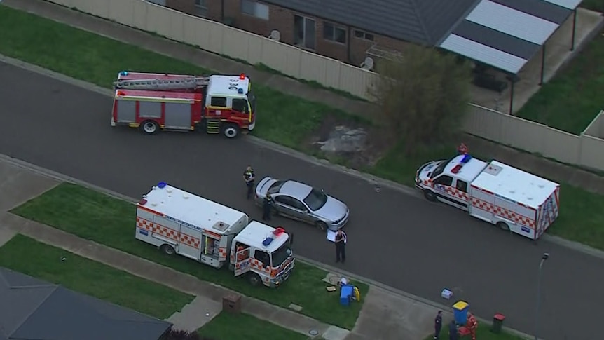 A car in the middle of the road, with fire trucks and SES vehicles surrounding it.