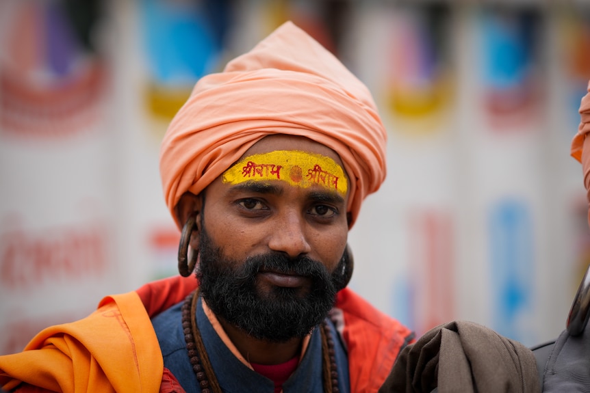 A man wearing orange turban and robes, with religious 