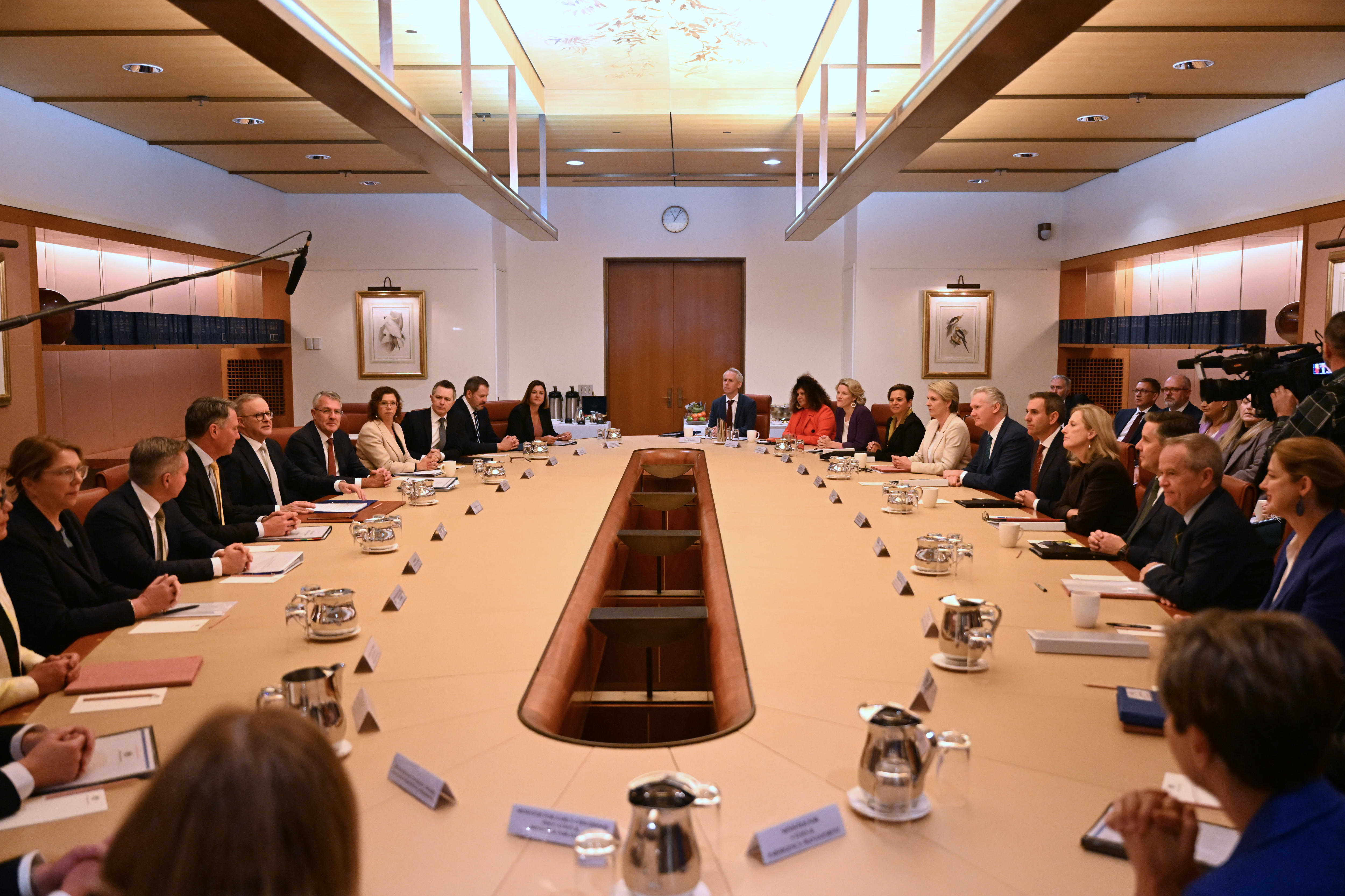 A group of politicians seated around a long oval-shaped meeting table inside a room