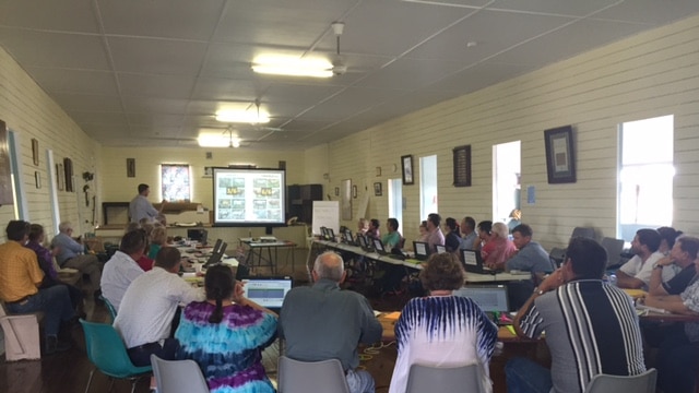 People sitting in a room looking at a presentation on a screen.