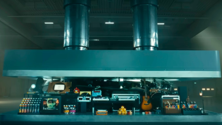 a STILL of the ad that shows a hydraulic press crushes an array of creative instruments. 