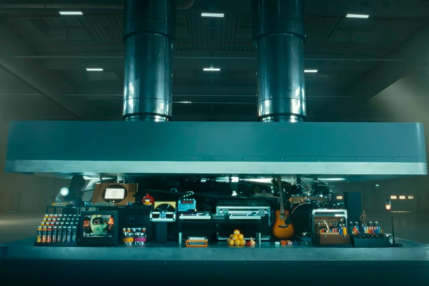 a STILL of the ad that shows a hydraulic press crushes an array of creative instruments. 