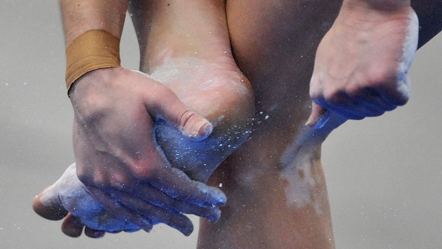 A female gymnast puts chalk on her feet.